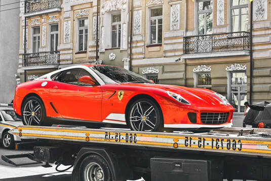 Red Ferrari being towed on a flatbed
